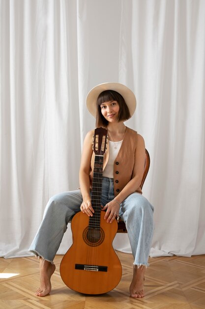 Junge Frau, die drinnen Gitarre spielt