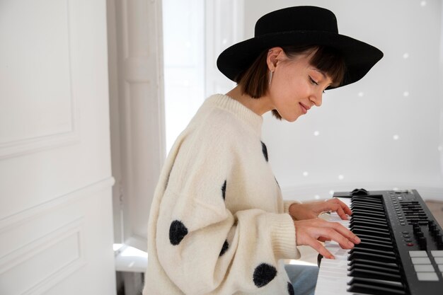 Junge Frau, die drinnen Klavier spielt