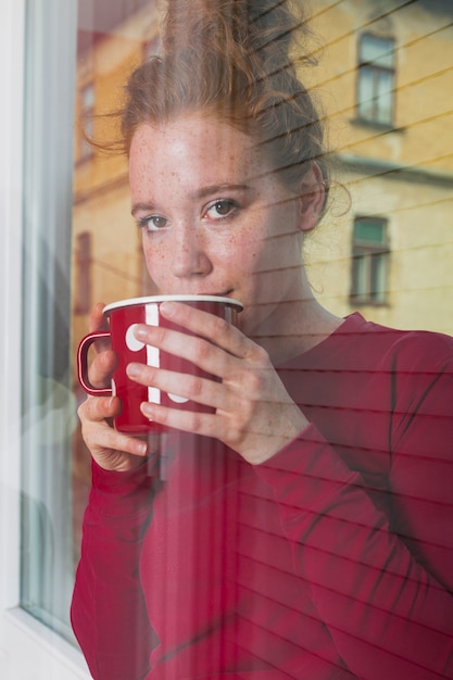 Kostenloses Foto junge frau, die durch fenster schaut