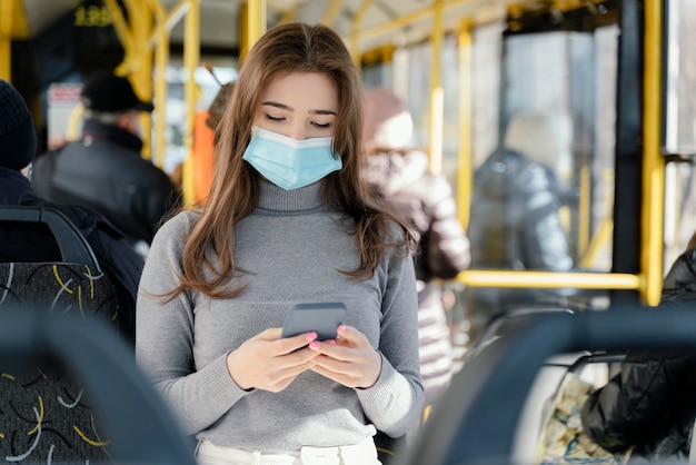 Junge Frau, die durch Stadtbus unter Verwendung des Smartphones reist