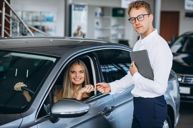 Junge Frau, die ein Auto von einem Autosalon prüft