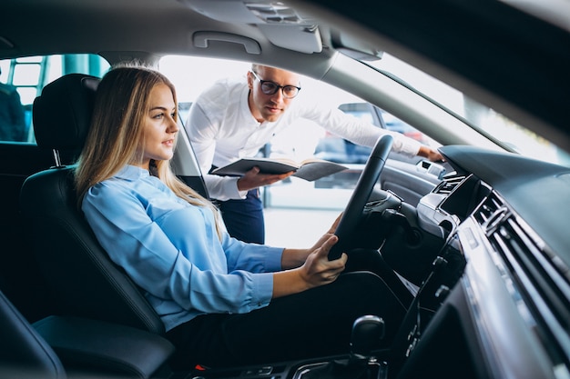 Junge frau, die ein auto von einem autosalon prüft