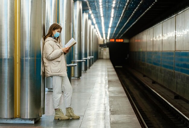 Junge Frau, die ein Buch in einer U-Bahnstation liest
