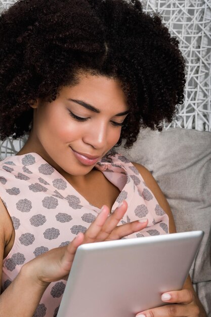 Junge Frau, die ein digitales Tablet verwendet, während sie sich zu Hause entspannt