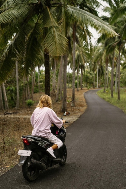 junge Frau, die ein tropisches Leben des Mopeds fährt