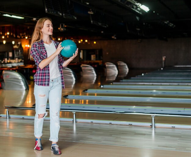 Junge Frau, die eine Bowlingkugel-Totale hält