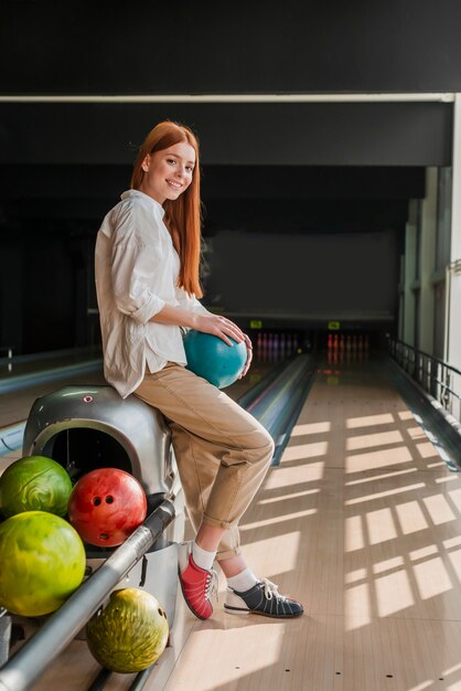 Junge Frau, die eine bunte Bowlingkugel hält