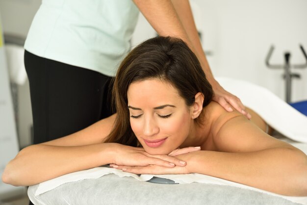 Junge Frau, die eine entspannende Rückenmassage in einer Badekurortmitte empfängt.