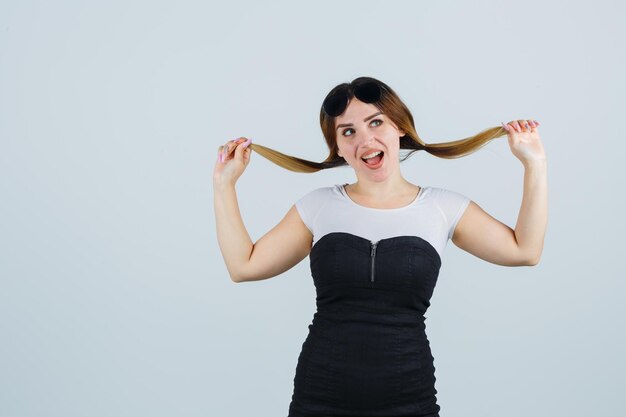 Junge Frau, die eine Haarsträhne hält und glücklich aussieht