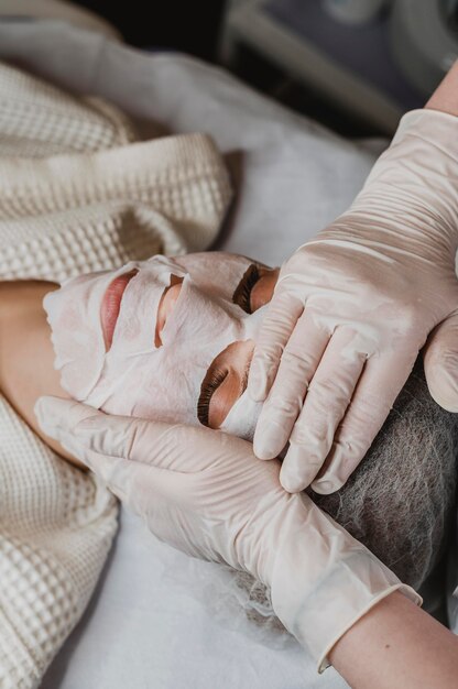 Junge Frau, die eine Hautmaskenbehandlung am Wellnesscenter erhält