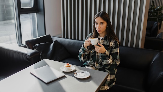 Kostenloses Foto junge frau, die eine kaffeepause genießt