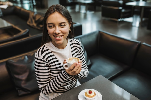 Junge Frau, die eine Kaffeetasse genießt