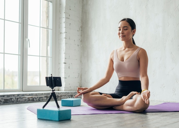 Junge Frau, die eine Meditationstechnik für einen neuen vlog zeigt