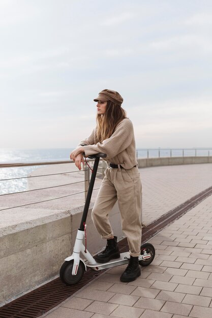 Junge Frau, die einen Elektroroller reitet