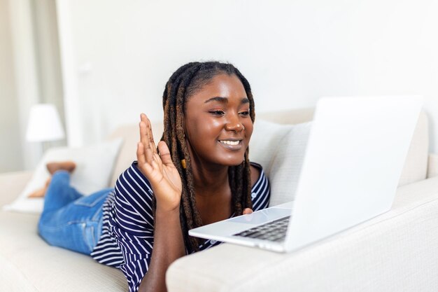 Junge Frau, die einen Online-Video-Chat mit Freunden über einen Laptop hat, überraschte den Ausdruck Frau kann nicht glauben, dass sie mit der Familie über einen Videoanruf spricht