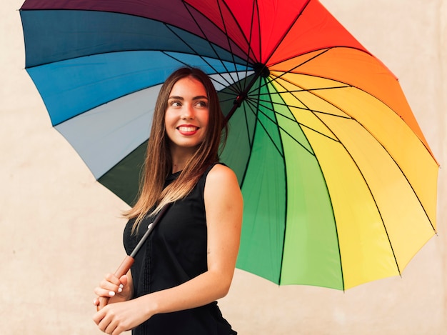 Junge Frau, die einen Regenbogenschirm hält