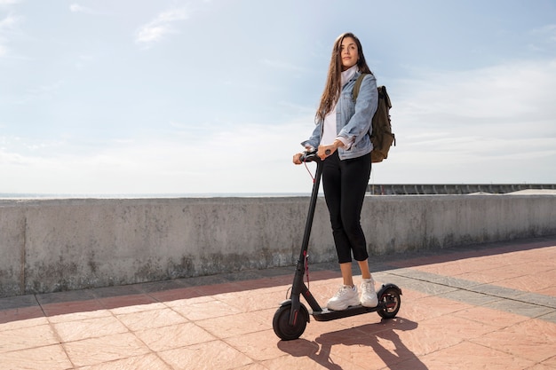 Junge Frau, die einen Roller im Freien benutzt