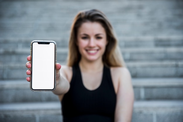 Kostenloses Foto junge frau, die einen smartphone hält