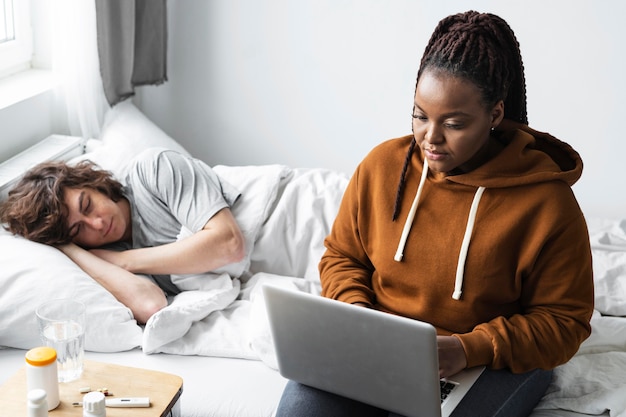 Junge Frau, die einen Videoanruf mit einem Arzt für ihren Freund hat