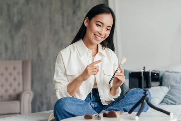 Junge Frau, die einen Vlog über Make-up drinnen macht