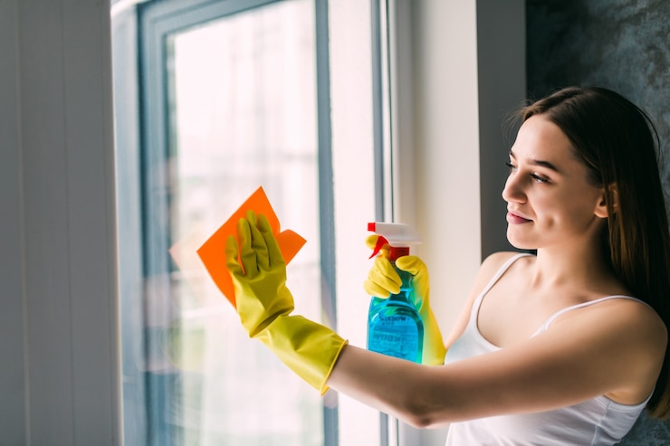 Kostenlose Foto junge frau, die fenster wäscht