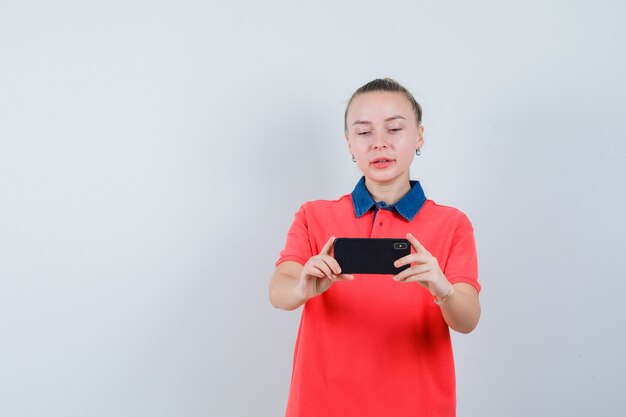 Junge Frau, die Foto auf Handy in der T-Shirt-Vorderansicht nimmt.