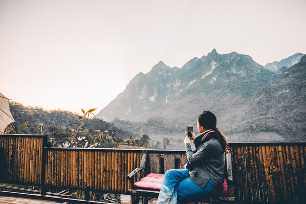 Junge Frau, die Foto mit ihrem Telefon von schönem Bergblick macht