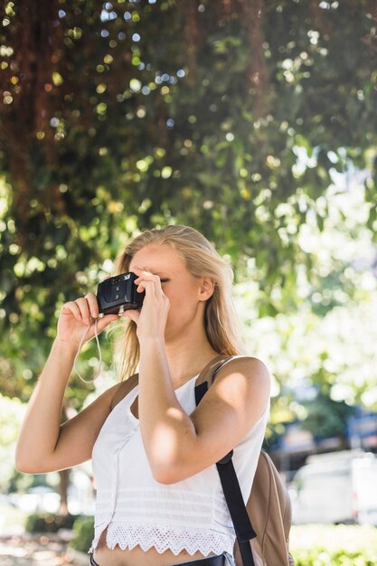 Junge Frau, die Foto von der Digitalkamera macht