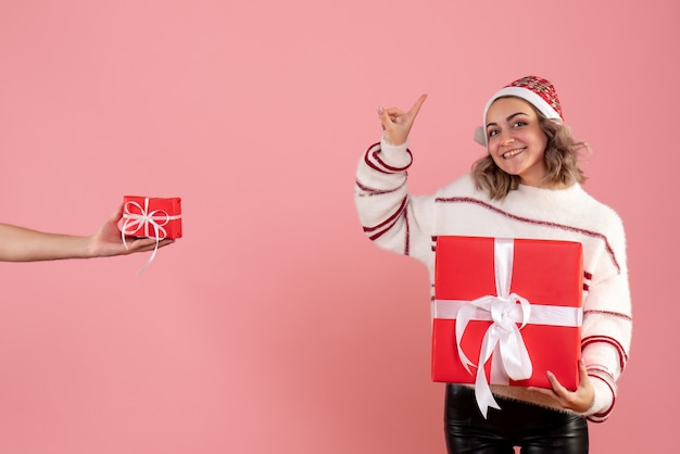 Junge frau, die geschenk hält und geschenk vom mann auf rosa annimmt