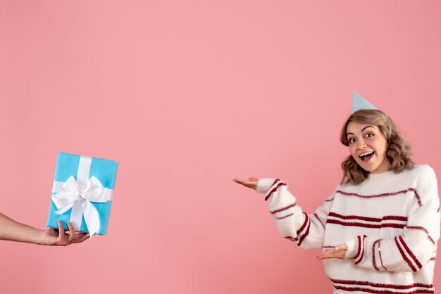 junge Frau, die Geschenk vom Mann auf rosa annimmt