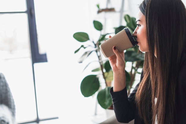 Junge Frau, die Getränk im Büro genießt