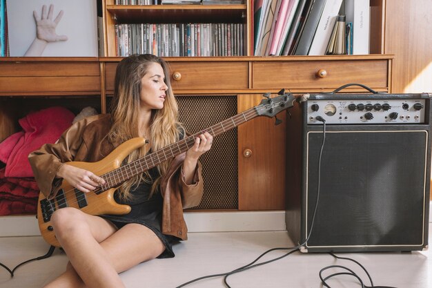 Junge Frau, die Gitarre auf Boden spielt