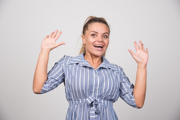 Junge Frau, die glücklich auf grauem Hintergrund steht.