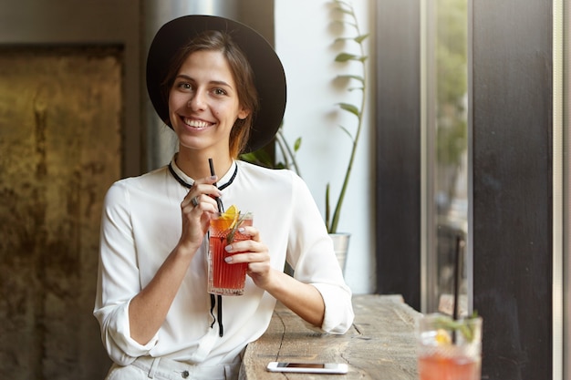 Junge Frau, die großen Hut im Café trägt