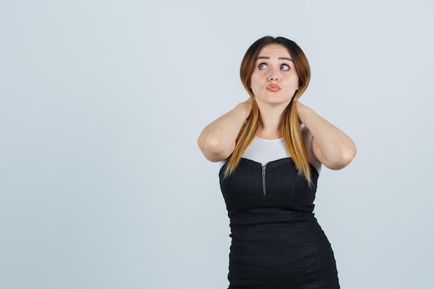 Junge Frau, die Haarsträhnen hält und nachdenklich aussieht