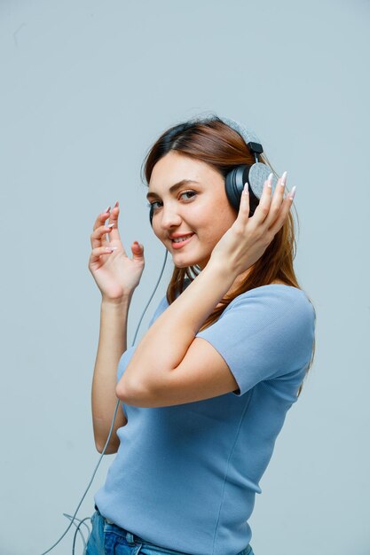 Junge Frau, die Hand an Kopfhörern hält, während sie Musik hört