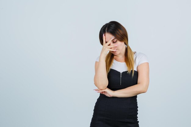 Junge Frau, die Hand im Gesicht hält und müde aussieht