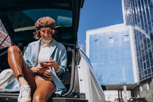 Junge Frau, die hinten im Auto sitzt und am Telefon spricht