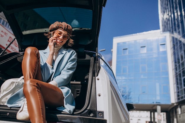 Junge Frau, die hinten im Auto sitzt und am Telefon spricht