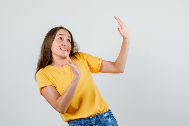 Junge Frau, die höflich Verweigerungsgeste in T-Shirt, Shorts zeigt und ängstlich aussieht