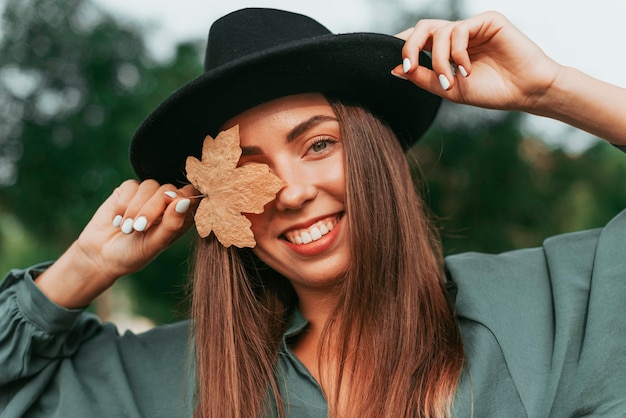 Junge Frau, die ihr Auge mit einem trockenen Blatt bedeckt