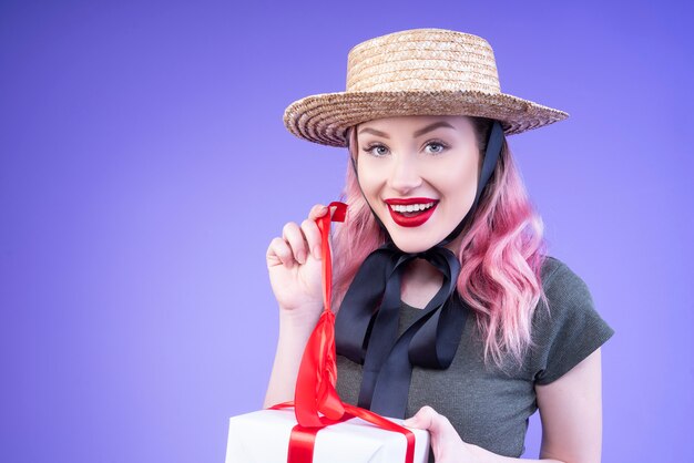 Junge Frau, die ihr Geschenk öffnet, verziert mit einem roten Band