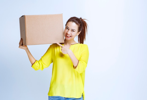 Junge Frau, die ihr Papppaket hält und es vorstellt