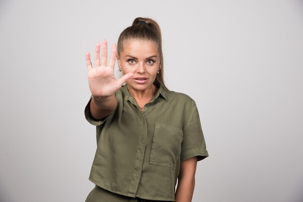 Junge Frau, die ihre Hand auf grauer Wand zeigt.