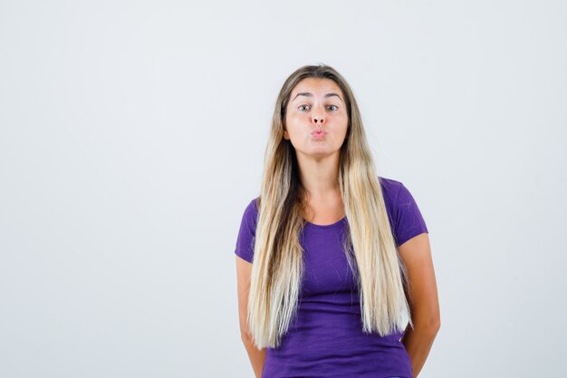 Junge Frau, die ihre Lippen in der Vorderansicht des violetten T-Shirts schmollt.