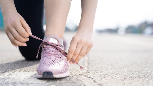 Junge Frau, die ihre Schnürsenkel beim Training im Freien, Straße bindet