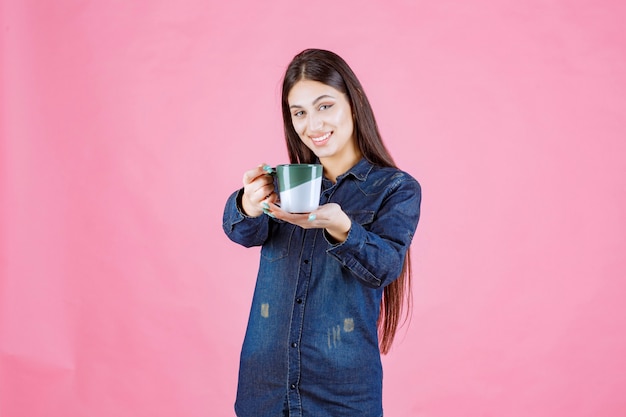 Junge Frau, die ihrem Freund eine Tasse Kaffee anbietet