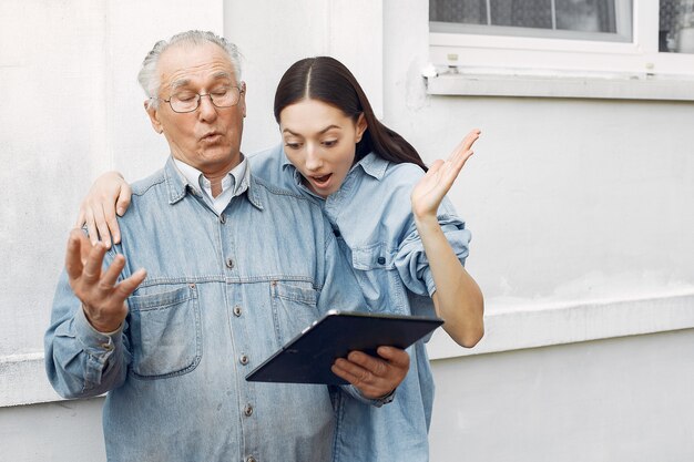 Junge Frau, die ihrem Großvater beibringt, wie man eine Tablette benutzt