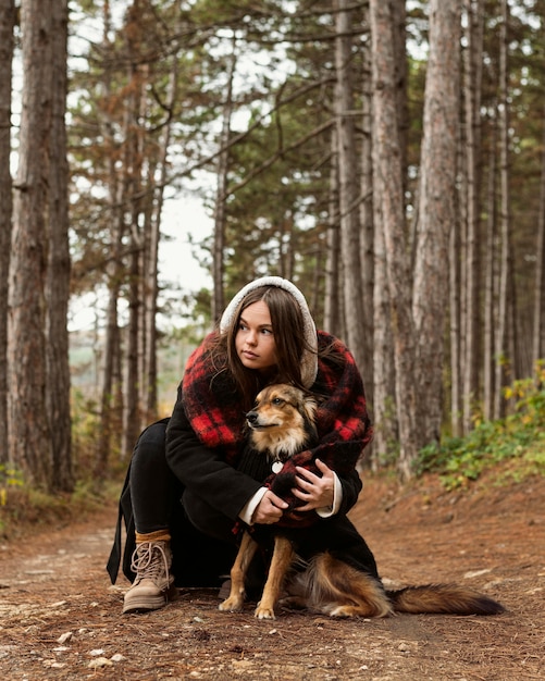 Junge Frau, die ihren Hund im Wald umarmt