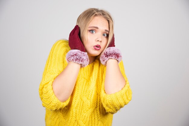 Junge Frau, die ihren Kopf berührt und in roten Handschuhen aufwirft.